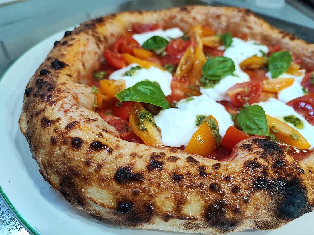 Pizza de borda alta com tomates-cereja, burrata e manjericão