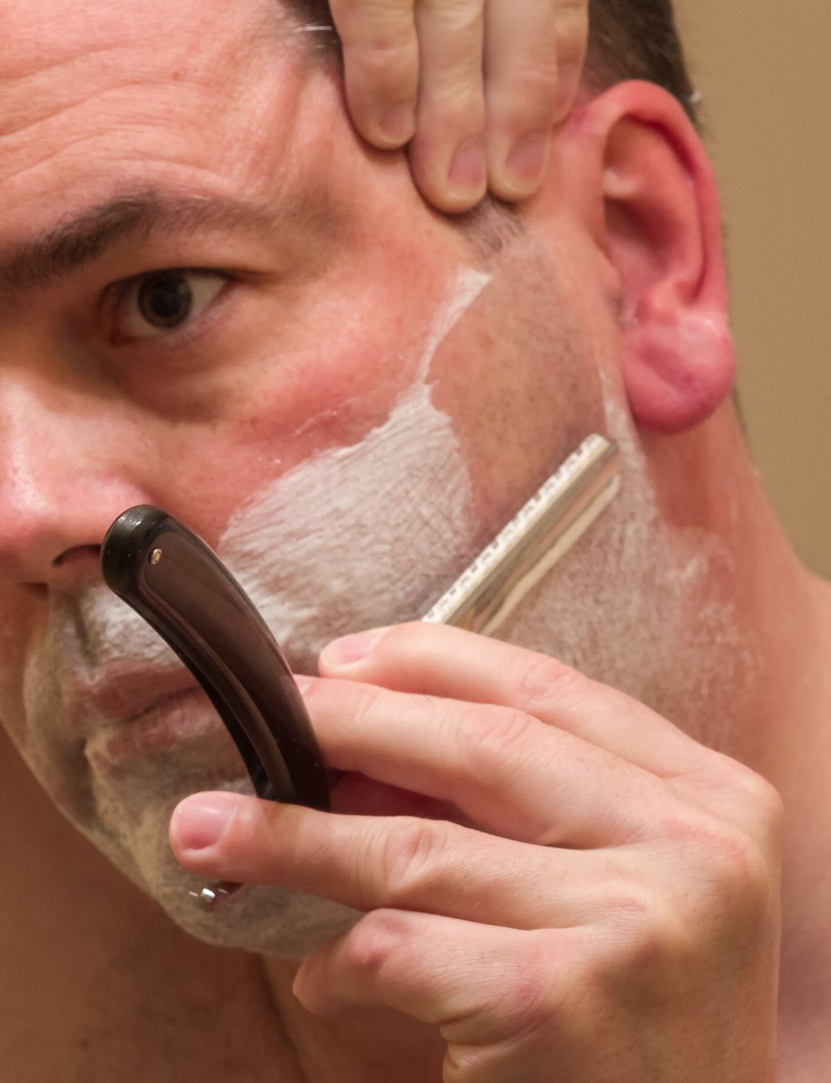 Homem fazendo a barba com uma navalha
