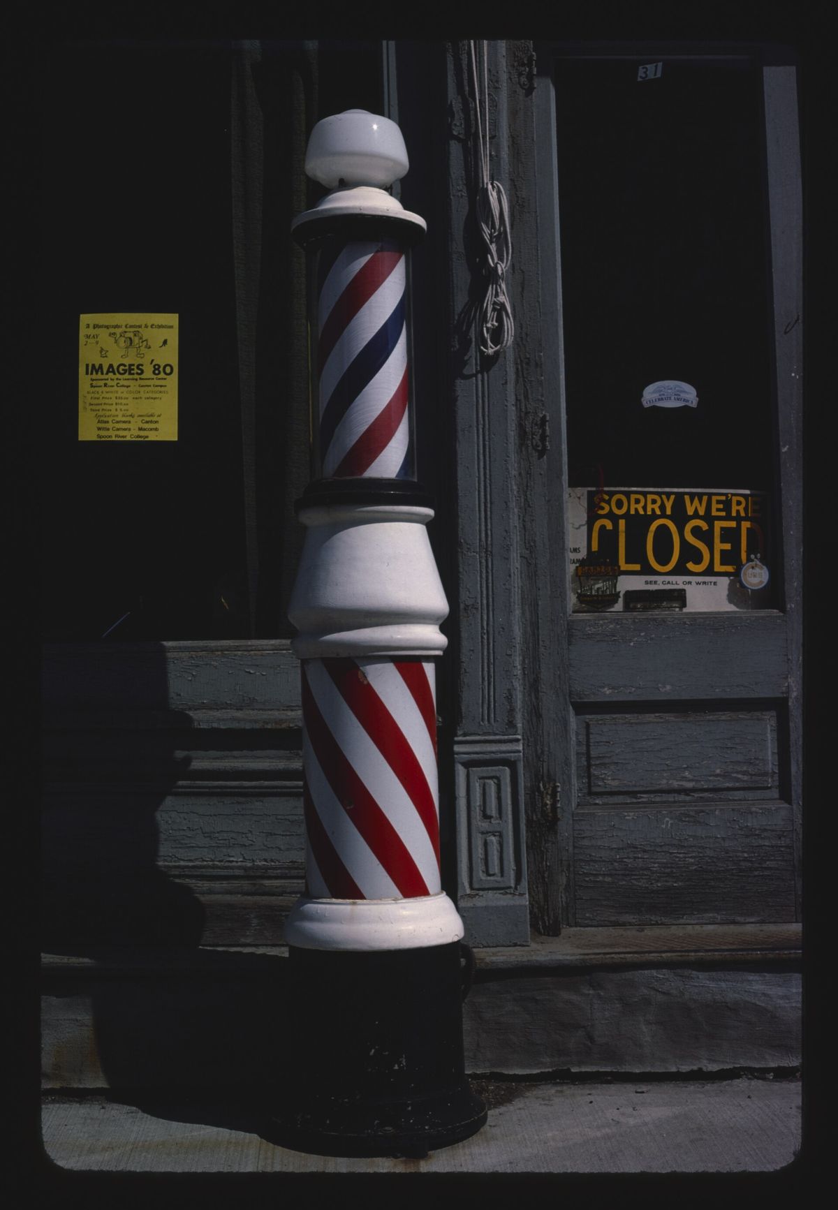 Poste de barbeiro listrado de vermelho e branco na porta de uma barbearia