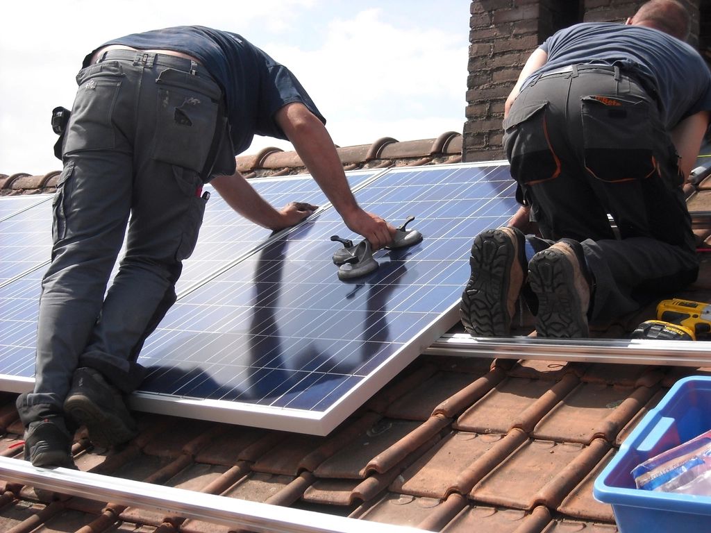 Dois instaladores fixando uma placa solar num telhado